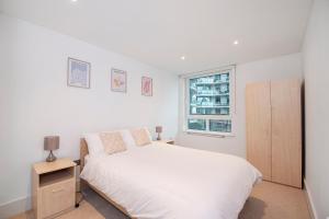 a white bedroom with a white bed and a window at Terraced riverview apartment in London