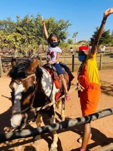 Ein junges Mädchen reitet mit einem Mann auf einem Pferd in der Unterkunft Quarto Barretos Country Resort in Barretos