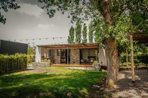 a house in a garden with a tree at Lodwine Lodge Apartments in Ciudad Lujan de Cuyo