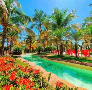 uma piscina de resort com palmeiras e cadeiras vermelhas em Quarto Barretos Country Resort em Barretos