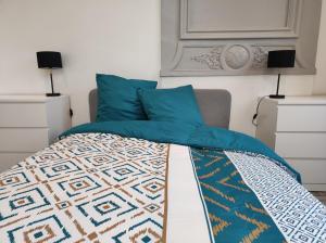 a bed with blue pillows and a quilt on it at La Marlienne - Appartement T3 dans un château 