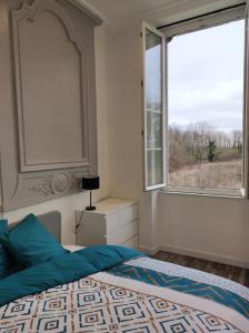 a bedroom with a bed and a large window at La Marlienne - Appartement T3 dans un château 