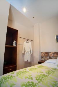 a bedroom with a bed and a white shirt on a rack at Apart hotel la Trejo in San Pedro Sula