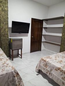 1 dormitorio con 2 camas y TV de pantalla plana en Casa Palmamar, en Olón