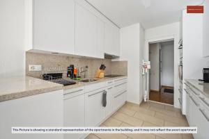 una cocina blanca con armarios y electrodomésticos blancos en Beautiful Boutique Apartment DRAHTZUG8 en Zúrich