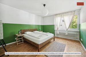 Schlafzimmer mit einem Bett mit grünen Wänden und einem Fenster in der Unterkunft Beautiful Boutique Apartment DRAHTZUG8 in Zürich