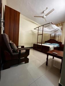 a bedroom with a bed and a chair and a table at Yahya Apartments in Ngambo