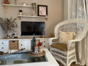 a living room with a wicker chair and a tv at MiraSierraHome... Tú hogar de vacaciones! in Alora