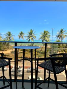 una mesa y sillas en un balcón con palmeras en Frente Mar Apartamento Luxuoso na praia de Cabo Branco, en João Pessoa