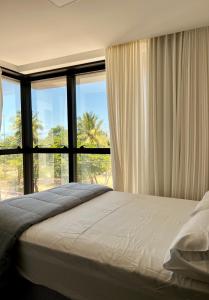 1 dormitorio con 1 cama y ventanas grandes en Frente Mar Apartamento Luxuoso na praia de Cabo Branco, en João Pessoa
