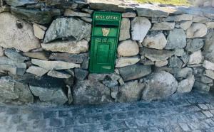 Maggie janes cottage Carlingford omealth في Ó Méith: صندوق بريد أخضر على جدار حجري