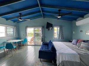 een blauwe slaapkamer met een bed en een tafel bij Dockside Utila Ocean front suites in Utila