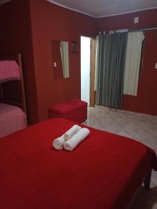 プエルトイグアスにあるRESIDENCIAL LOS AMIGOSの赤い壁のベッド2台が備わるホテルルームです。