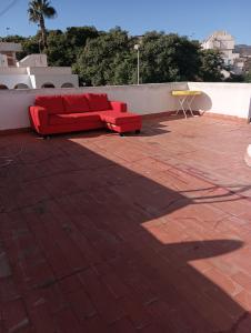 eine rote Couch auf einer Backsteinterrasse in der Unterkunft Apartamento en Puerto de Mazarrón in Puerto de Mazarrón