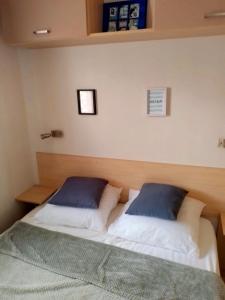a bedroom with a bed with two pillows on it at Camping, mobil home équipé proche du lac de Sainte Croix et des gorges du Verdon in Sainte-Croix-de-Verdon