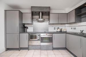 una cucina con armadietti bianchi ed elettrodomestici in acciaio inossidabile di 2 Bed 2 Bath Close to Big Ben a Londra