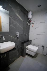 La salle de bains est pourvue d'un lavabo blanc et de toilettes. dans l'établissement Hotel Suncity, à Ahmedabad