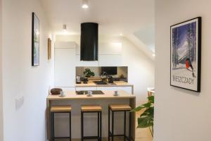 a kitchen with a sink and a counter with stools at Apartamenty Parkowa 9 in Lesko