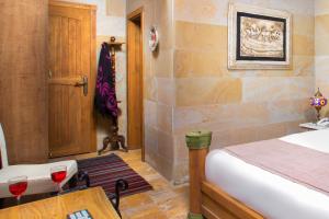 a bedroom with a bed and two glasses of wine at Katapa Stone House in Goreme