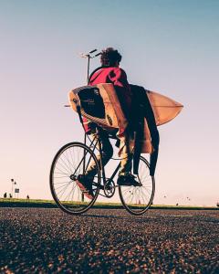 a man riding a bike with a surfboard on it at Hostel Playa Grande Güemes in Mar del Plata +81 photos