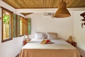 Un dormitorio con una cama con un libro encima. en Casa Baleia - Caraíva - 100m da Igreja, en Caraíva