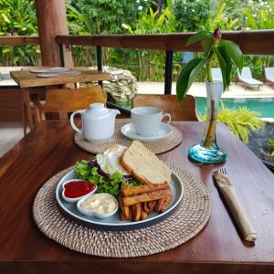 stół z talerzem jedzenia z kanapką i frytkami w obiekcie Sunrise Paradise Bali w mieście Karangasem