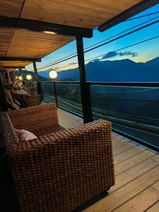 balcón con sillas de mimbre y vistas a las montañas en Mo Huai Su-桃園市民宿085號 en Hualing