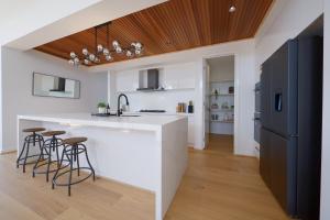 a kitchen with a white counter and bar stools at Modern Spacious Coastal Villa in Ocean Grove
