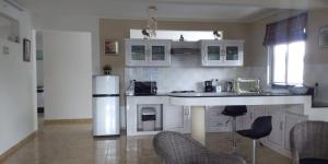 a kitchen with white cabinets and a counter with chairs at Real Mauritius Apartments in Grand Gaube