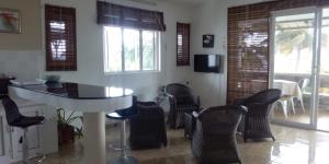 uma sala de estar com cadeiras, uma mesa e janelas em Real Mauritius Apartments em Grand Gaube