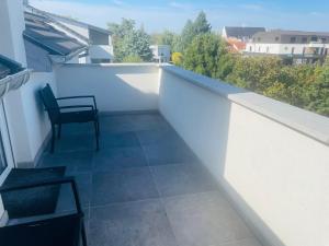 a balcony with a chair on a white wall at Appartement Bes,, Attique neuf avec confort in Wittenheim