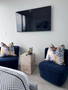 sala de estar con 2 sillas azules y TV en Delight Luxurious Apartments en Johannesburgo
