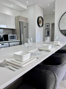 Una cocina con una mesa con platos y copas de vino. en Delight Luxurious Apartments, en Johannesburgo