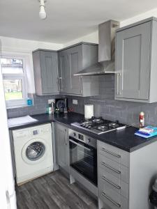 een keuken met een fornuis en een wasmachine bij Lovely 2-Bed fully refurbished House in London in Londen