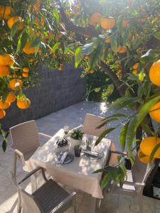 una mesa y sillas sentadas bajo un naranjo en Casa vacanza Il Mandarino, en Viagrande