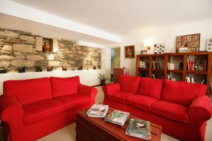 una sala de estar con sofás rojos y una pared de piedra. en Casa Dos Poços, en Vilar Torpim
