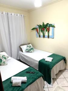 duas camas num quarto com lençóis verdes e toalhas em Quarto Ponta Negra em Angra dos Reis