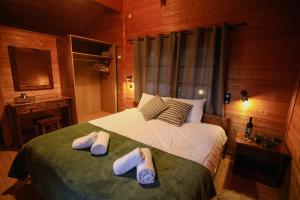 1 dormitorio con 1 cama con 2 zapatillas en Τετραπολις Wellness Farm, 