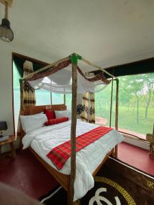 a bedroom with a canopy bed and a window at Doublegsafaris and camp mikumi in Mikumi