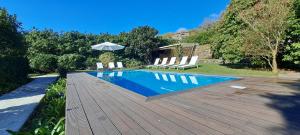 uma piscina com cadeiras e um guarda-sol num deque de madeira em Carmo Country Villas em Ponta Delgada