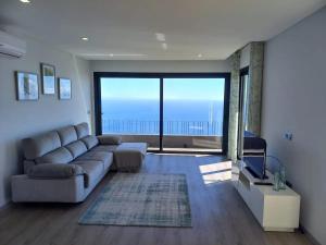 a living room with a couch and a large window at Apartamento Domingos in Arco da Calheta