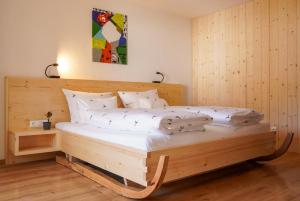 a bedroom with a wooden bed with white pillows at Appartementhaus Bergkristall in Kartitsch