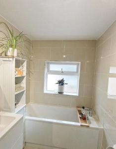 a bathroom with a tub and a window and a plant at Homestay close to the hospital and Alton Towers with resident dog and cat in Stoke on Trent