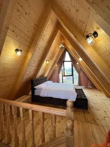 a bed in the attic of a log cabin at Windmill Shkodra Gesthouse Camping & Grill in Shkodër