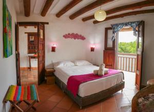 a bedroom with a large bed and a balcony at Hotel Casa El Mandarino in Barichara