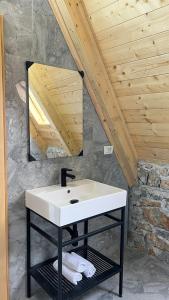 a white sink in a bathroom with a wooden ceiling at Windmill Shkodra Gesthouse Camping & Grill in Shkodër