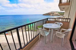 un balcone con tavolo e sedie e l'oceano di Marsalforn Seaview Apartment in a quiet area a Qbajjar