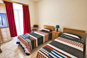 2 letti in una camera con tende rosse di Marsalforn Seaview Apartment in a quiet area a Qbajjar