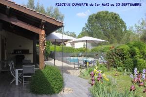 een patio met een tafel en stoelen en een parasol bij Les sittelles in Gaillac