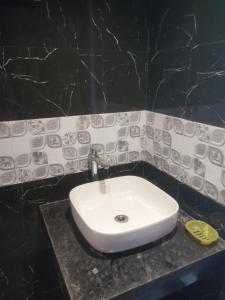 a white sink in a black bathroom at Samarth Homestay in Ratnagiri